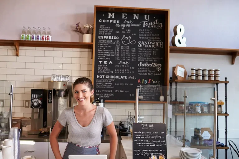 Caballete de pizarra en la entrada de una cafeter&iacute;a de especialidad con un mensaje escrito en tiza l&iacute;quida.