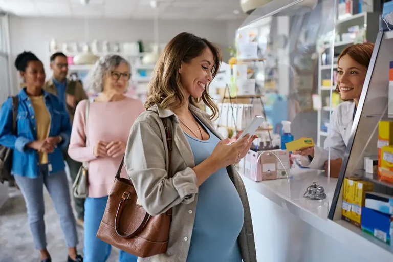 Cliente retirando un ticket de un sistema de turnos en el mostrador de un comercio local.